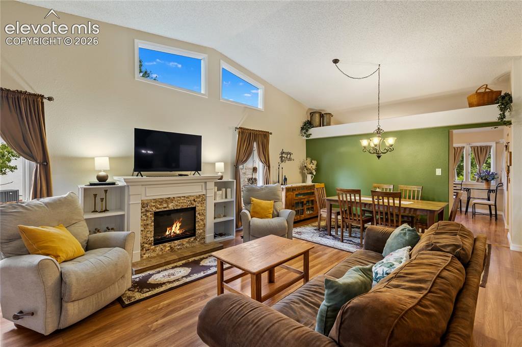 Image 17 of 43: Living features vaulted ceilings, easy care laminate flooring. The fireplac