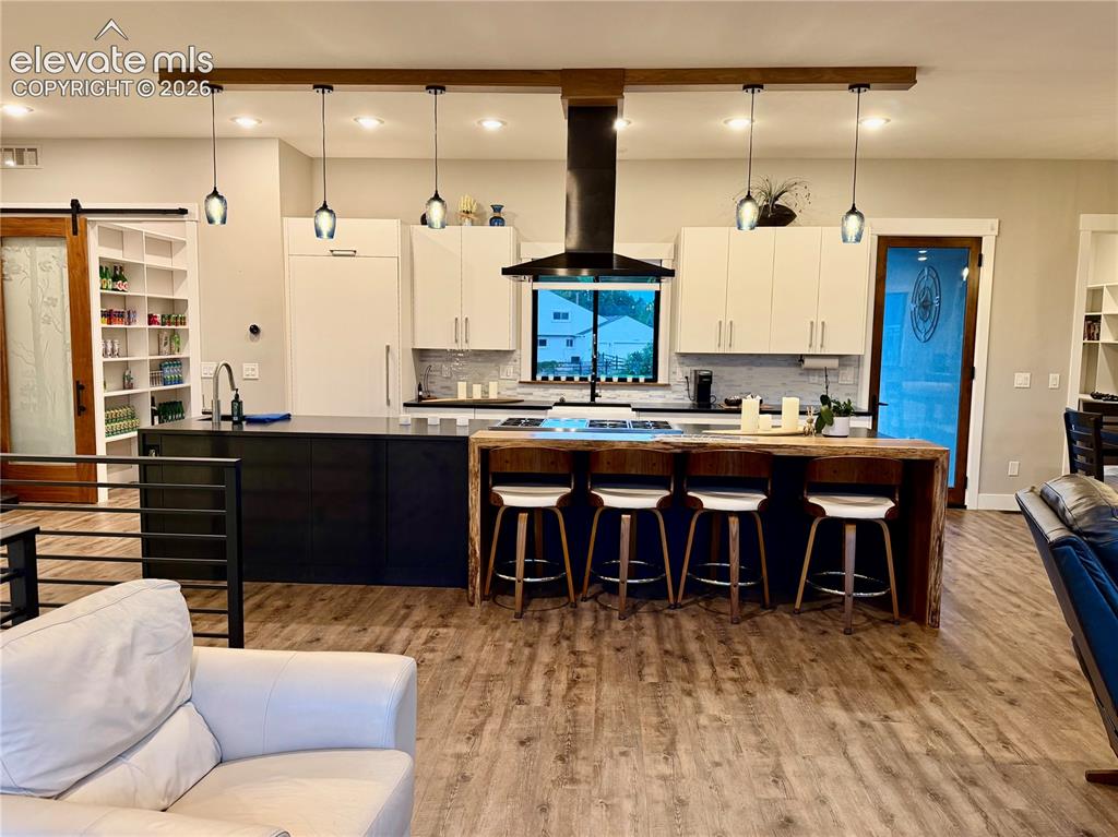 Image 10 of 49: Wood-finish flooring throughout, kitchen with contrasting cabinetry and a c