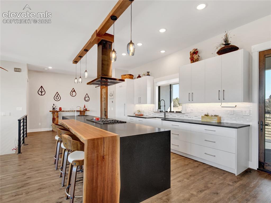 Image 12 of 49: Modern kitchen featuring a large island with a live-edge wood breakfast bar