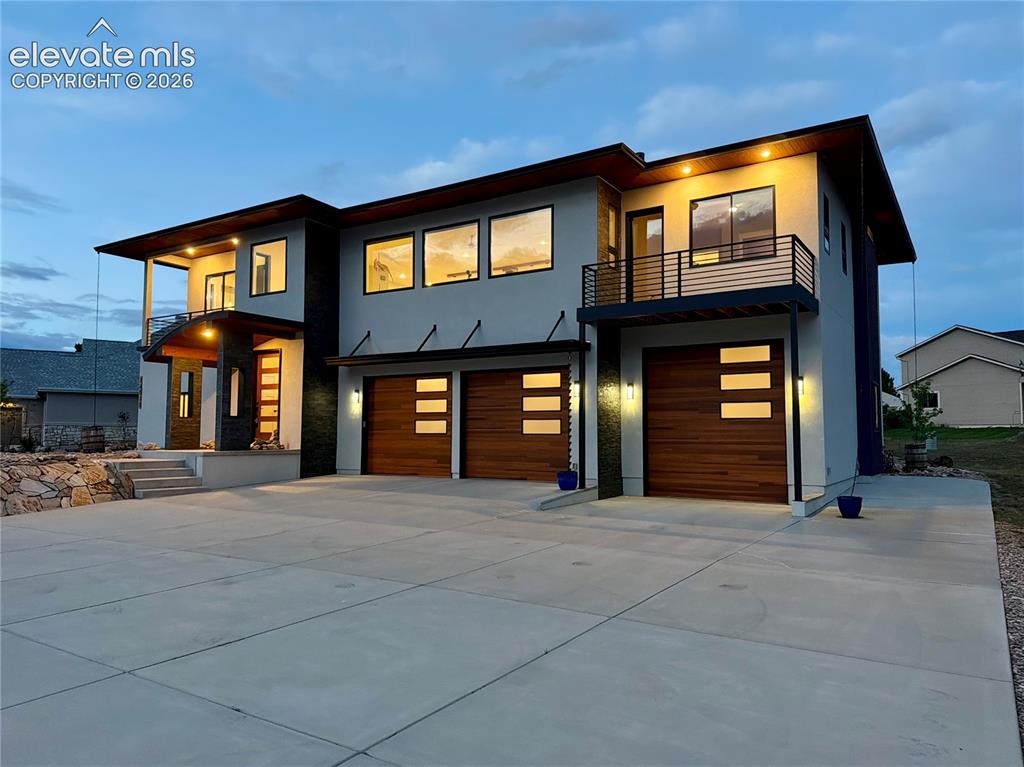 Image 2 of 49: Modern architectural exterior featuring a prominent two-car garage with woo