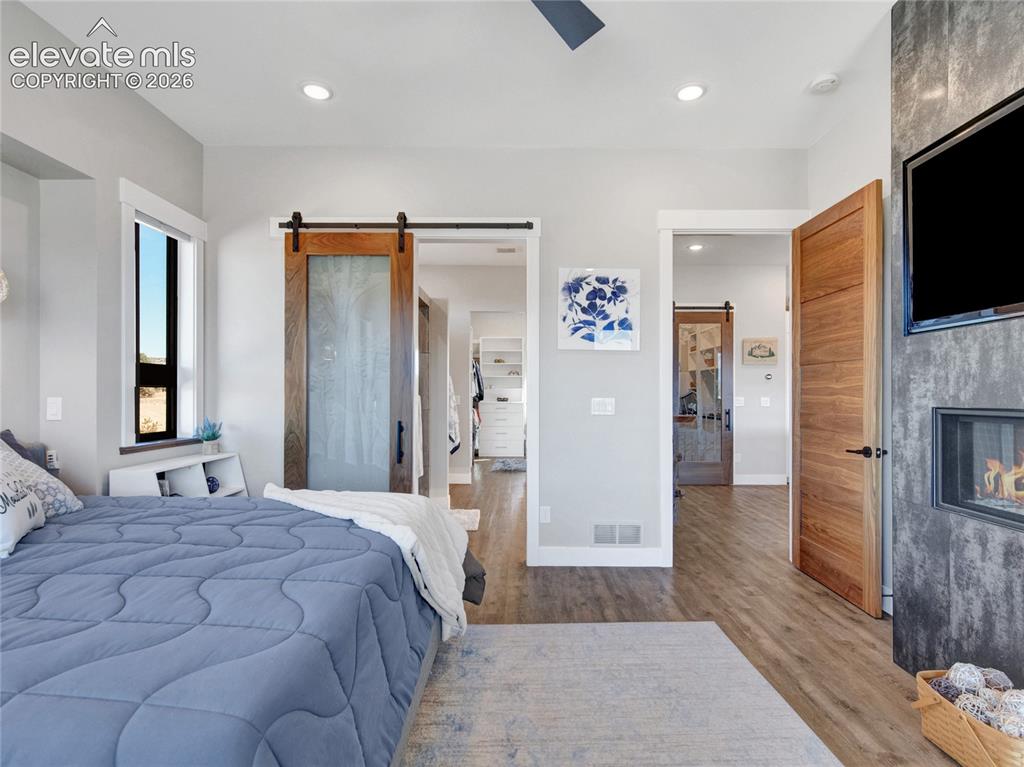 Image 24 of 49: Primary bedroom with a modern ceiling fan and gas fireplace.