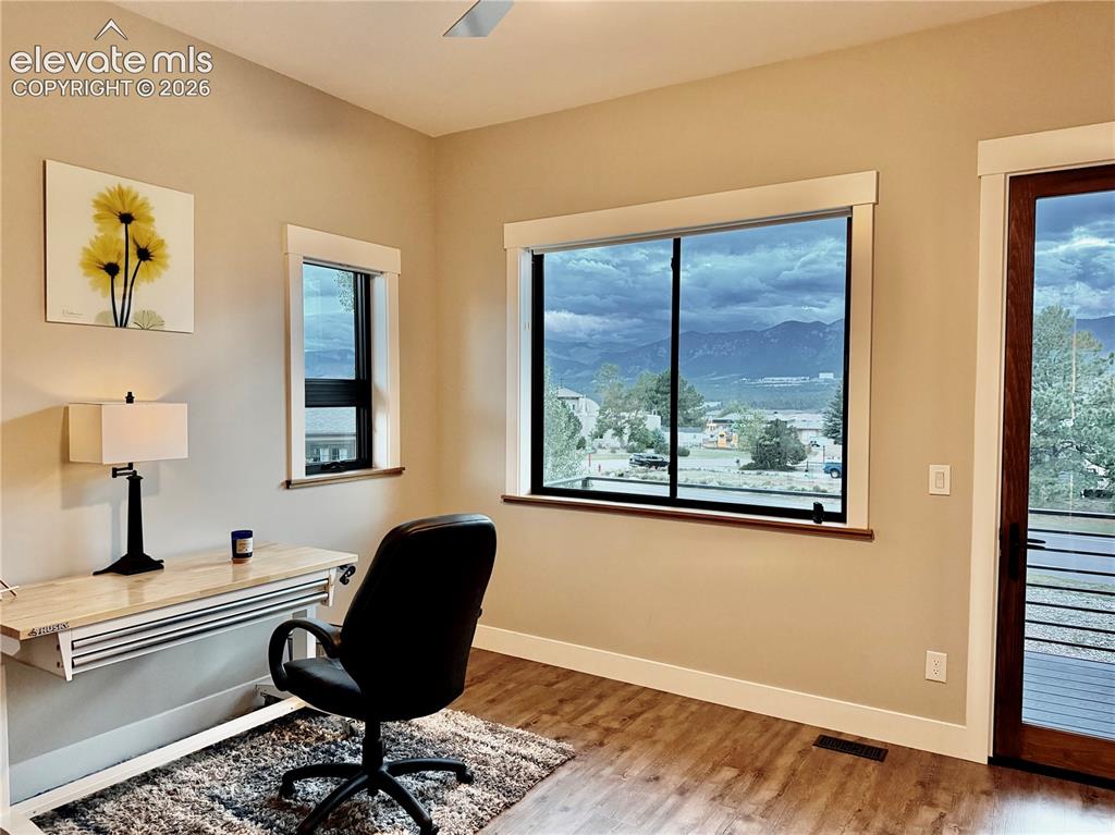 Image 29 of 49: Expansive windows with mountain scenery, wood-finish flooring, light-toned