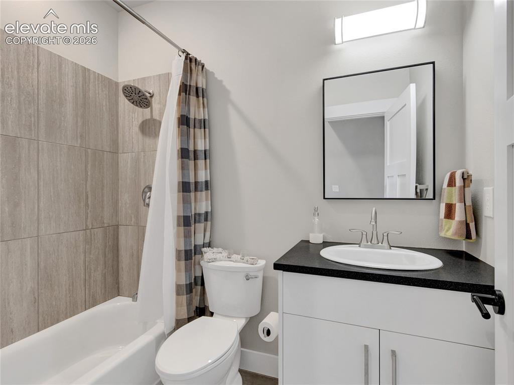 Image 33 of 49: Bathroom featuring a white vanity with dark countertop, undermount sink, an