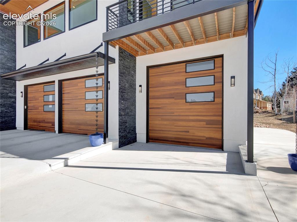 Image 37 of 49: Contemporary exterior with a five-car garage with RV storage featuring wood