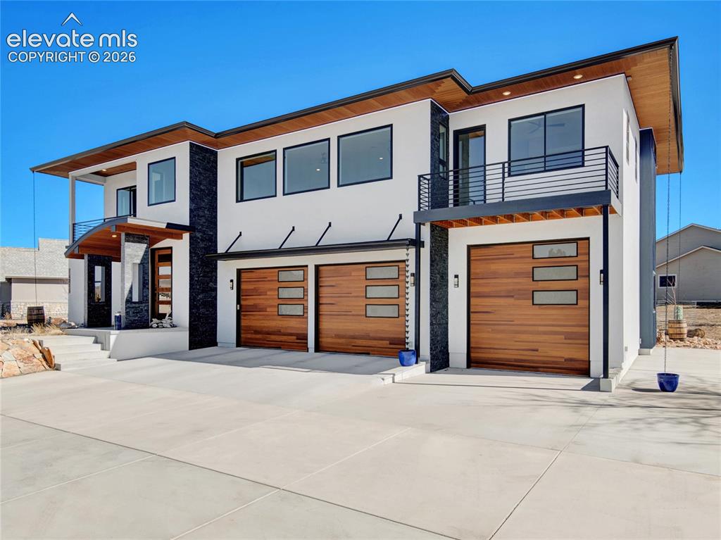 Image 45 of 49: Contemporary exterior featuring crisp white stucco, dark stone accents, and