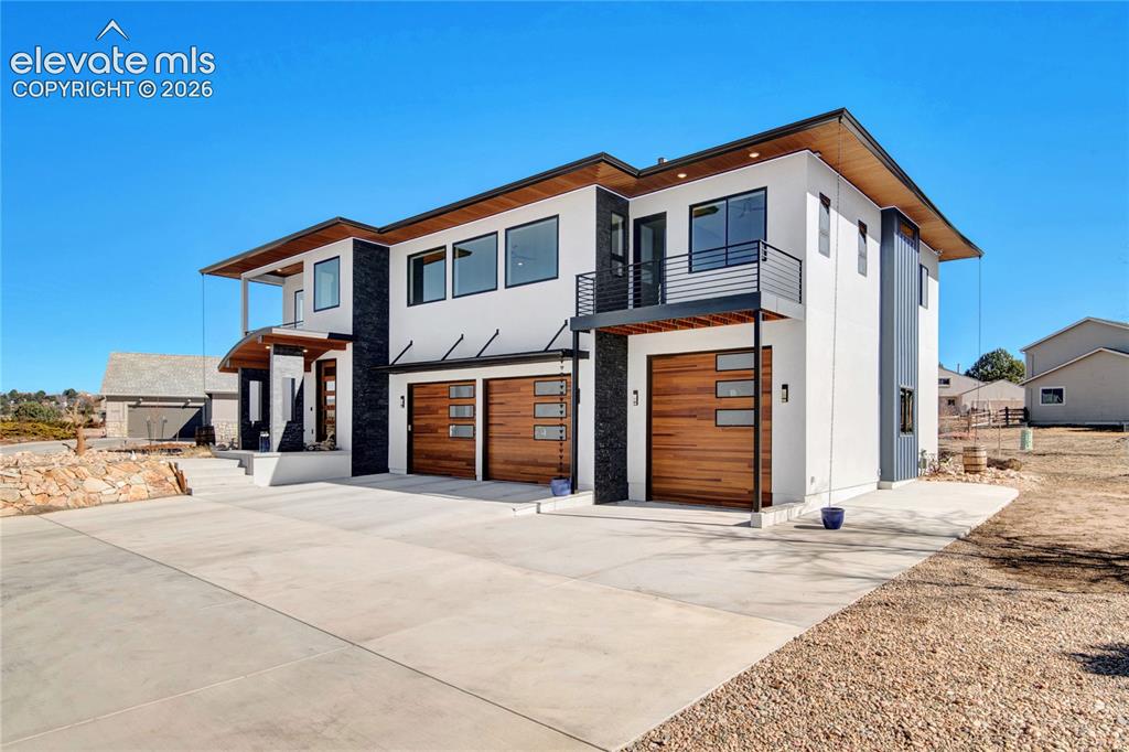 Image 46 of 49: Modern architectural design featuring a white stucco exterior with dark acc