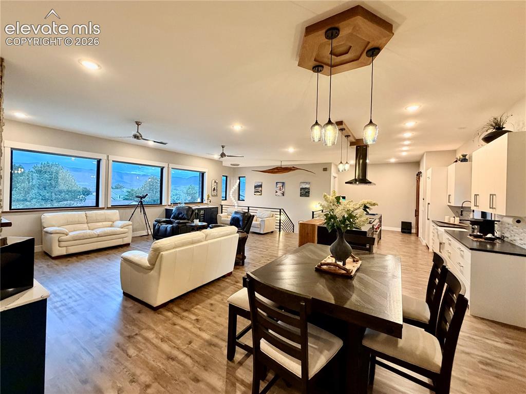 Image 7 of 49: Open-concept living area with wood-finish flooring, recessed lighting, and