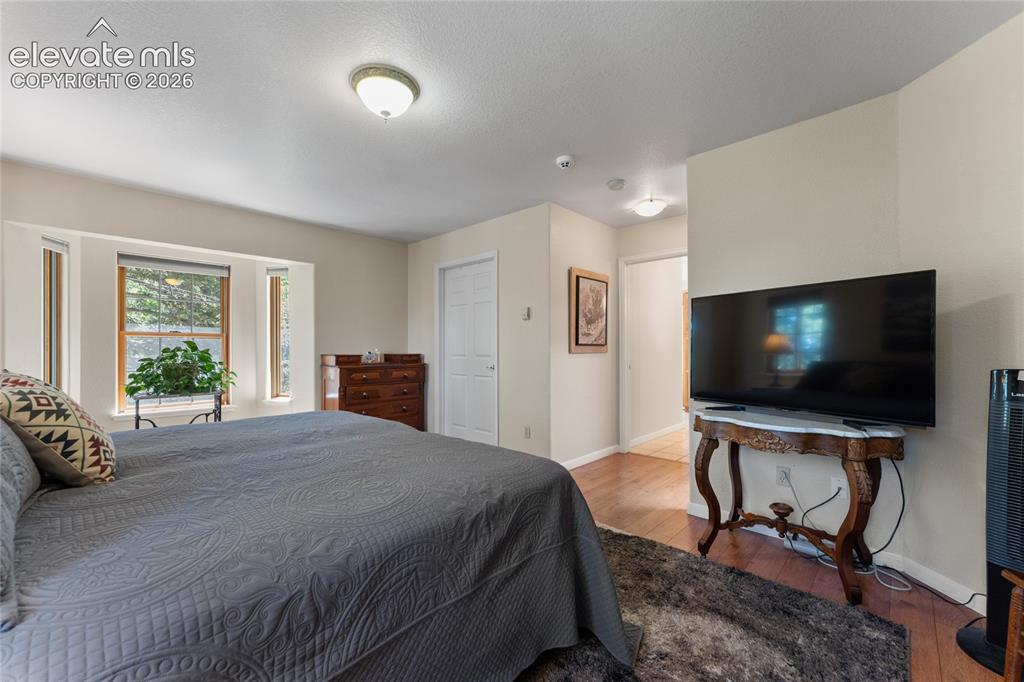 Image 11 of 43: Bedroom featuring multiple windows, recessed lighting, and wood-finish floo