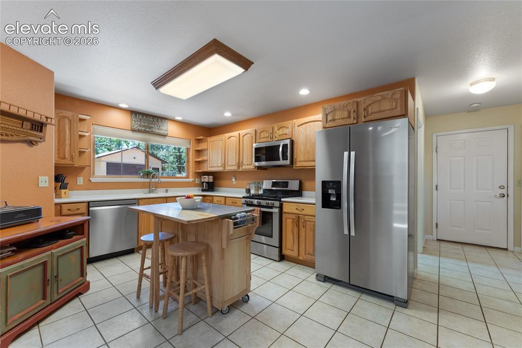 Image 15 of 43: Kitchen featuring oak cabinetry, stainless steel appliances, a center islan