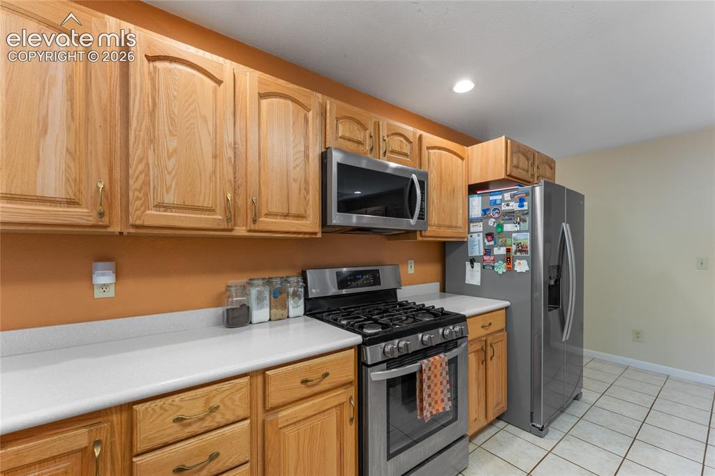 Image 18 of 43: Kitchen featuring light wood cabinetry, stainless steel appliances, white c