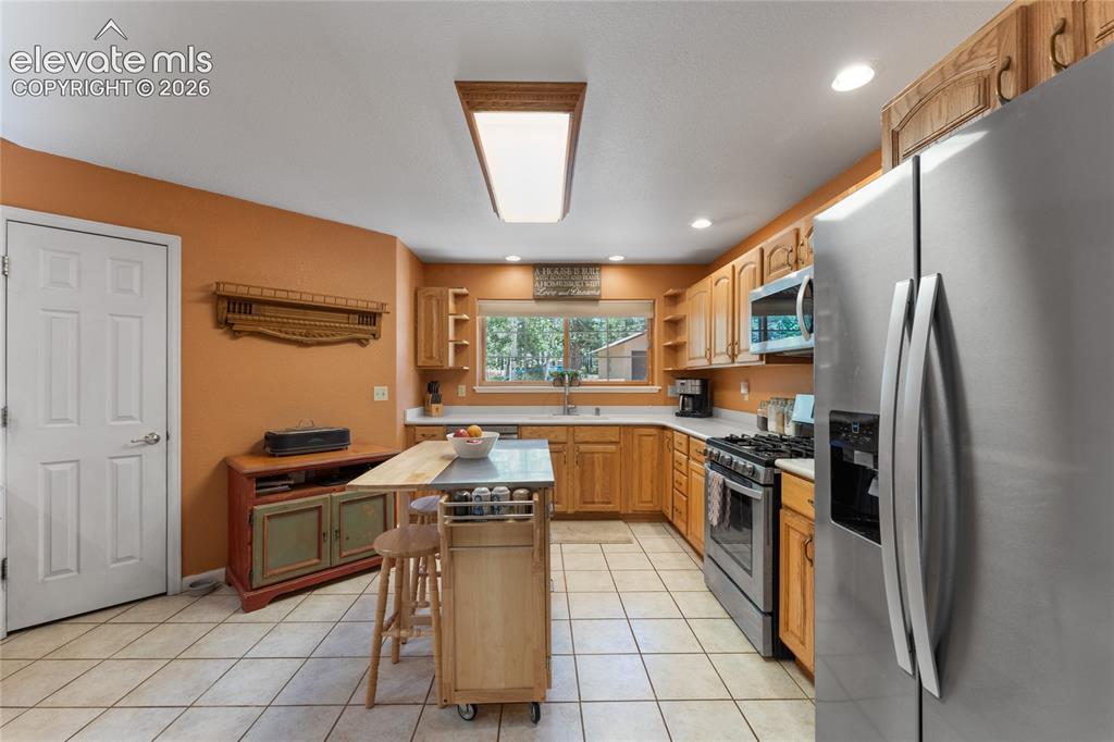 Image 20 of 43: Kitchen featuring tile flooring, wood cabinetry, stainless steel appliances