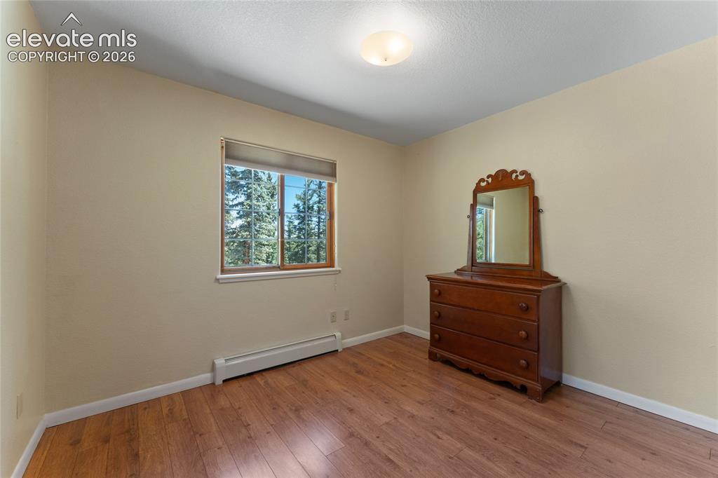 Image 22 of 43: Room with wood-finish flooring, neutral wall paint, and a window with a nat