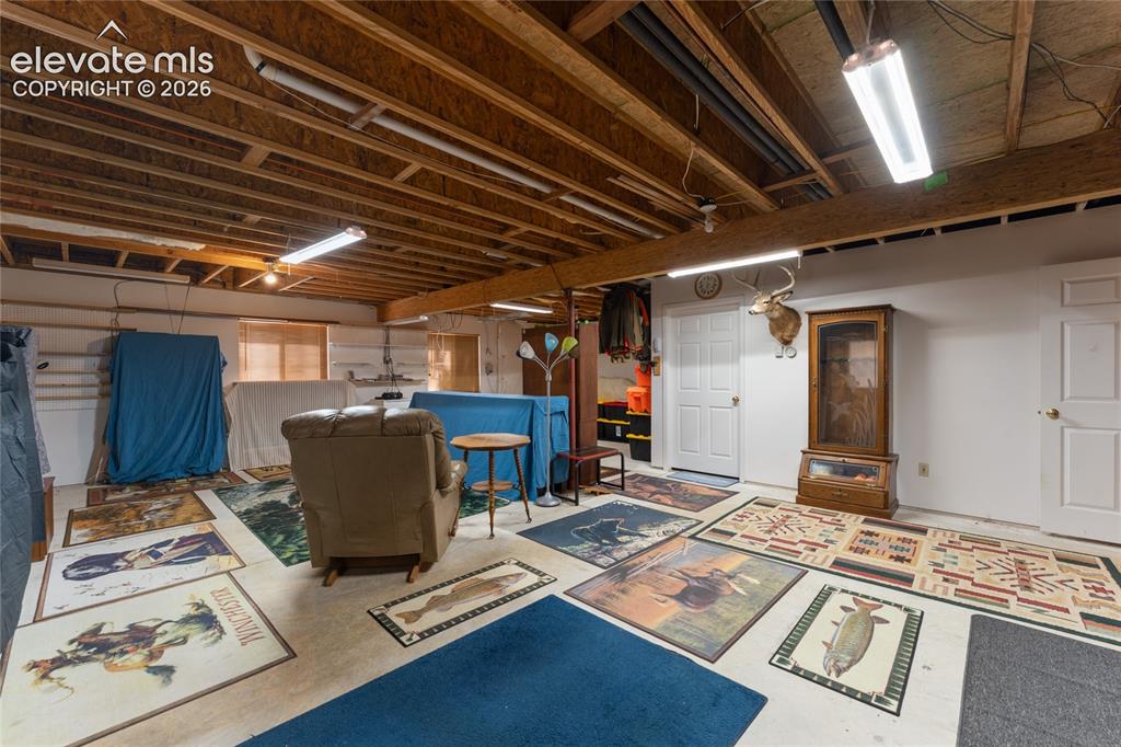 Image 32 of 43: Spacious lower level with exposed ceiling joists and fluorescent lighting