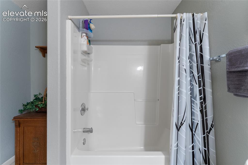 Image 34 of 43: White fiberglass tub and shower combination with chrome fixtures