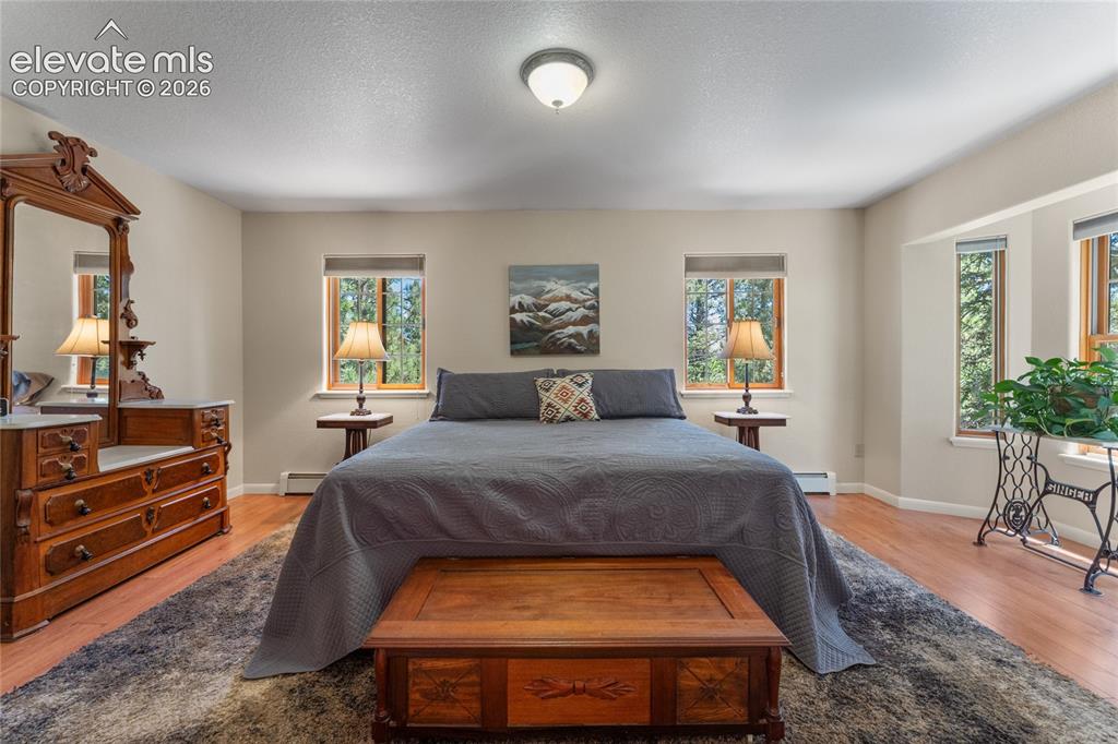 Image 8 of 43: Spacious room featuring wood-finish flooring, light-toned walls, multiple w