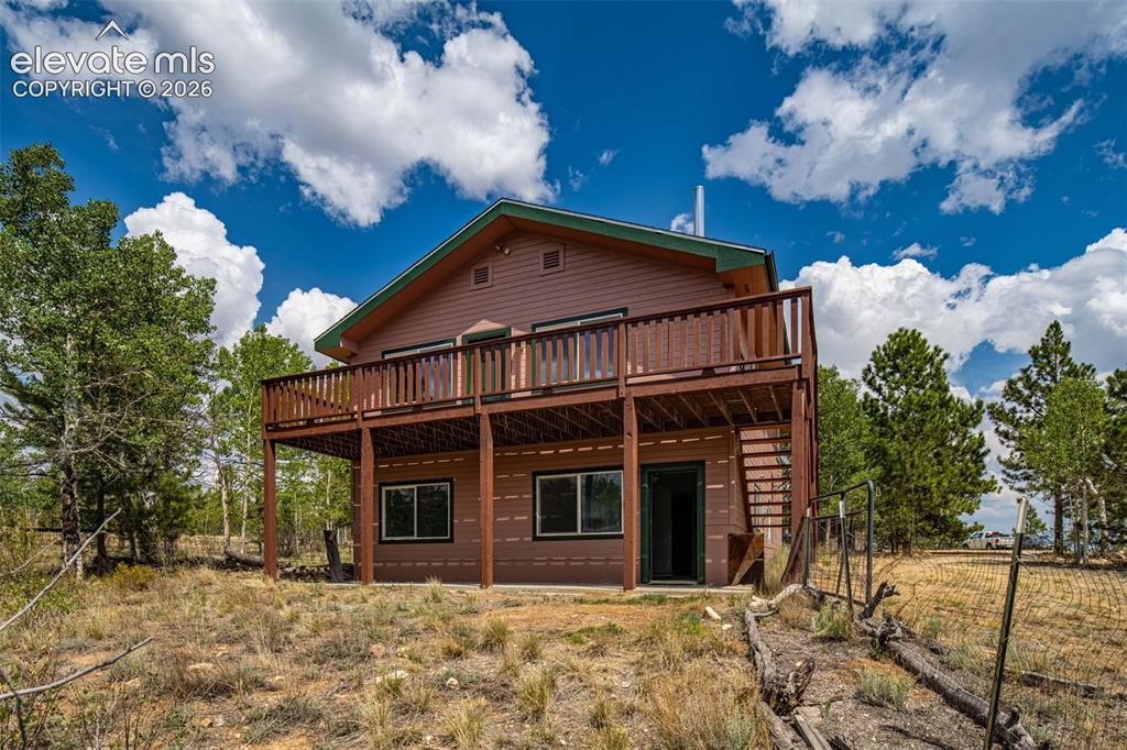 Image 2 of 49: Two-story residence with an elevated deck, multiple windows, and a lower-le