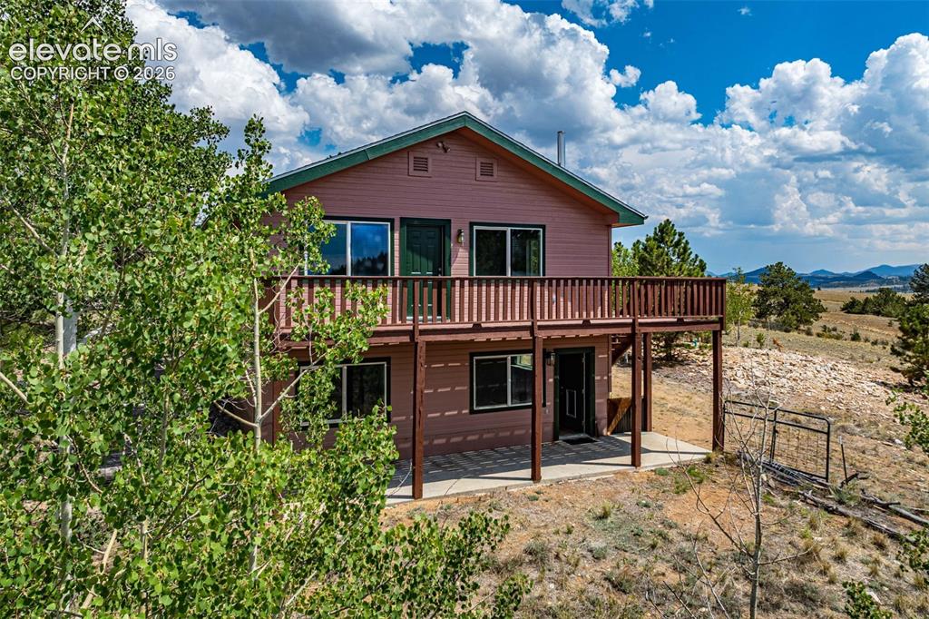 Image 3 of 49: Two-story residence featuring a wood-sided exterior and a second-level deck
