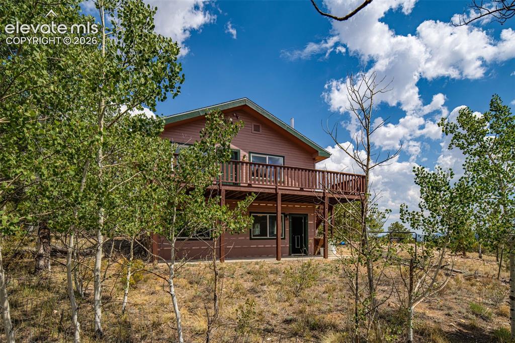 Image 4 of 49: Two-story residential structure featuring a prominent upper-level deck, gro