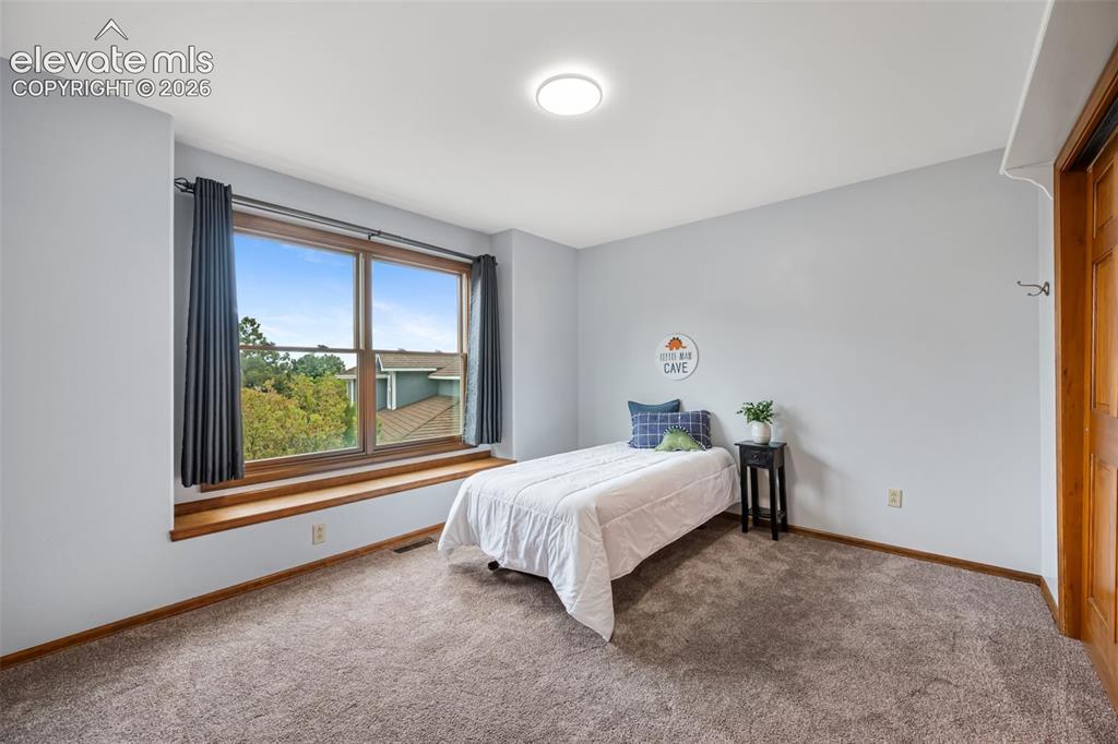 Image 21 of 36: Main level bedroom/office with built ins, double sided fireplace and warm h