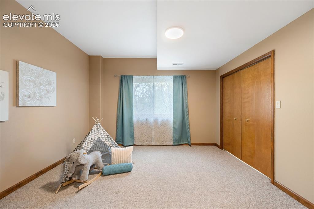 Image 23 of 36: Upper level primary bedroom with window seat, tray ceilings and sitting are