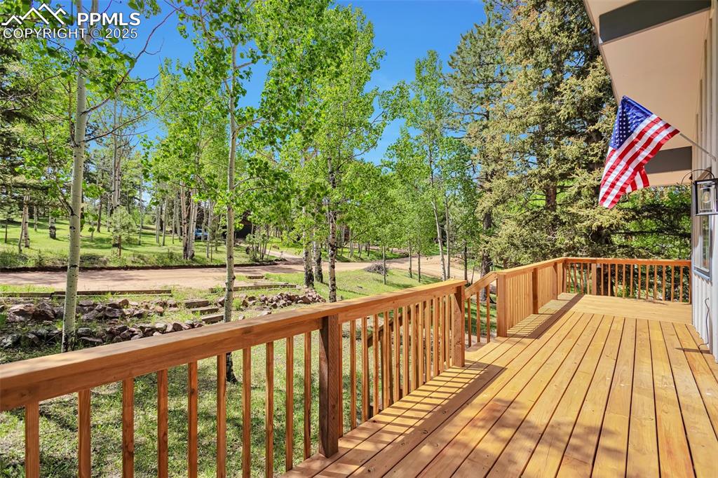 Image 28 of 33: Wooden deck featuring view of wooded area and a lawn