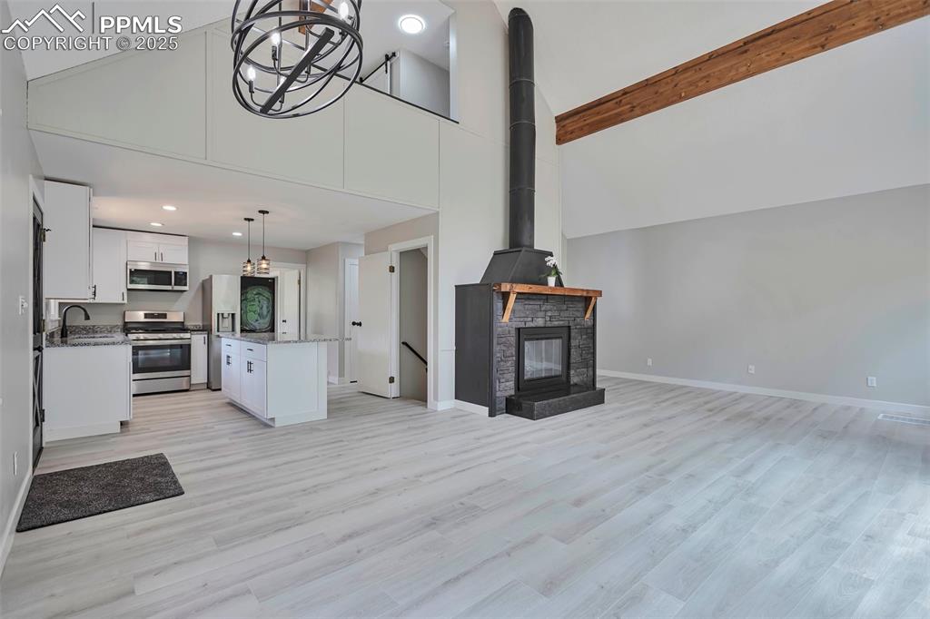 Image 8 of 33: Living room featuring high vaulted ceiling and beamed ceiling.