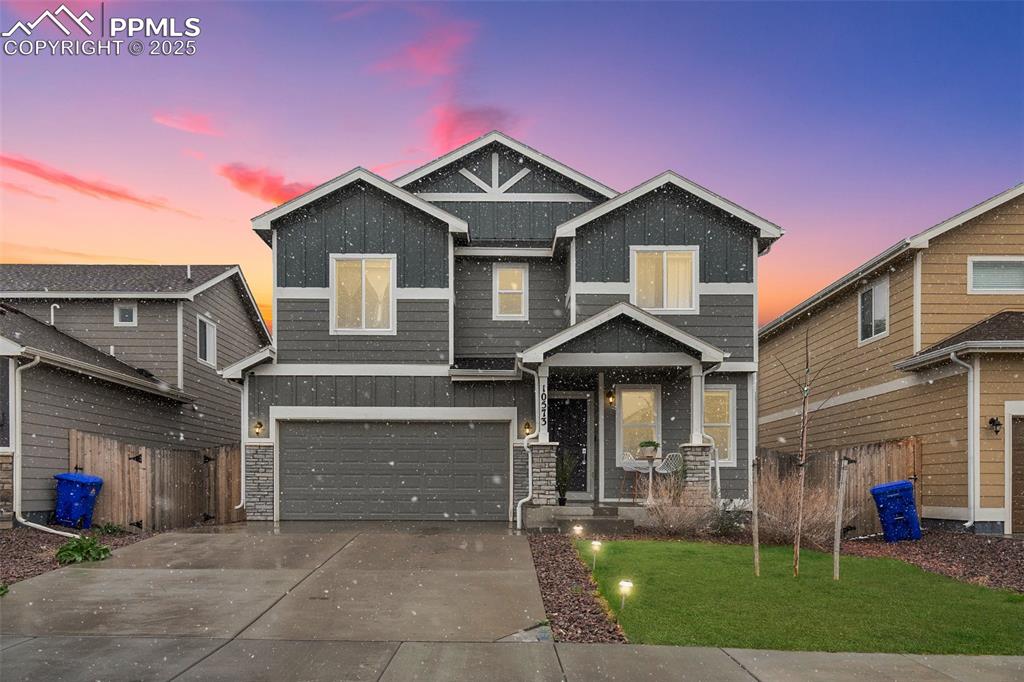 Caption: View of front of property featuring board and batten siding, an attached garage, and driveway