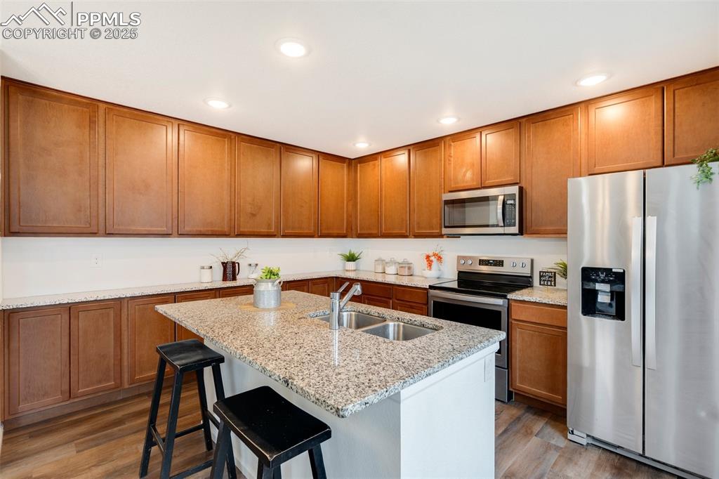 Image 14 of 29: Kitchen with stainless steel appliances, a sink, wood finished floors, ligh