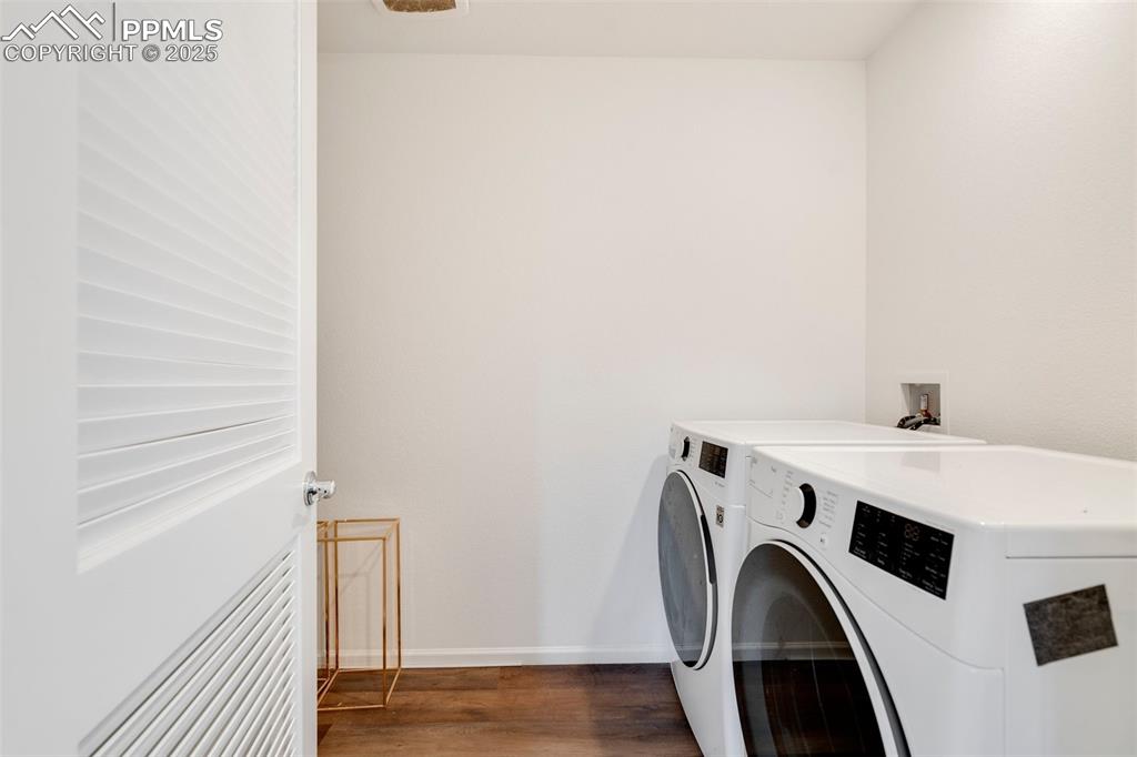 Image 16 of 29: Clothes washing area featuring washing machine and dryer, baseboards, wood 