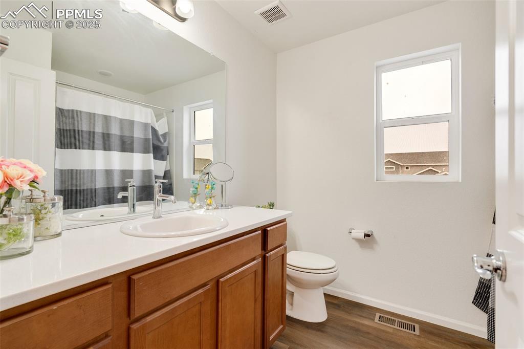 Image 26 of 29: Full bath featuring wood finished floors, visible vents, toilet, and basebo