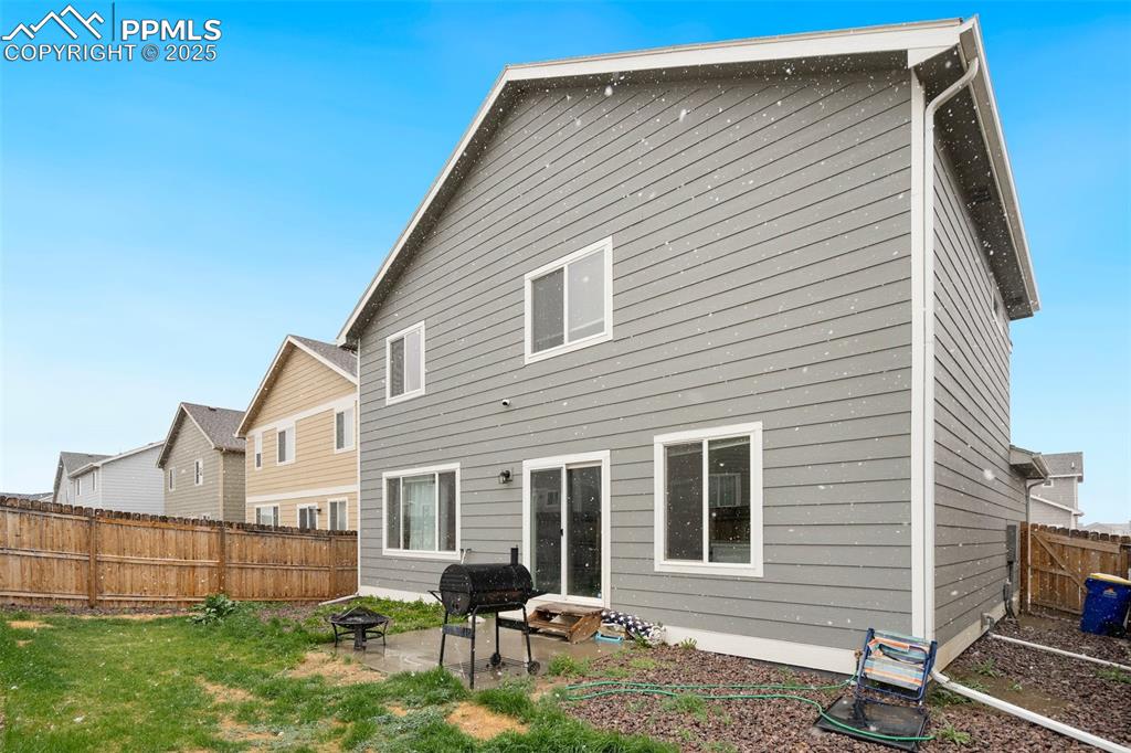 Image 28 of 29: Rear view of house featuring a fenced backyard, a patio, and a lawn