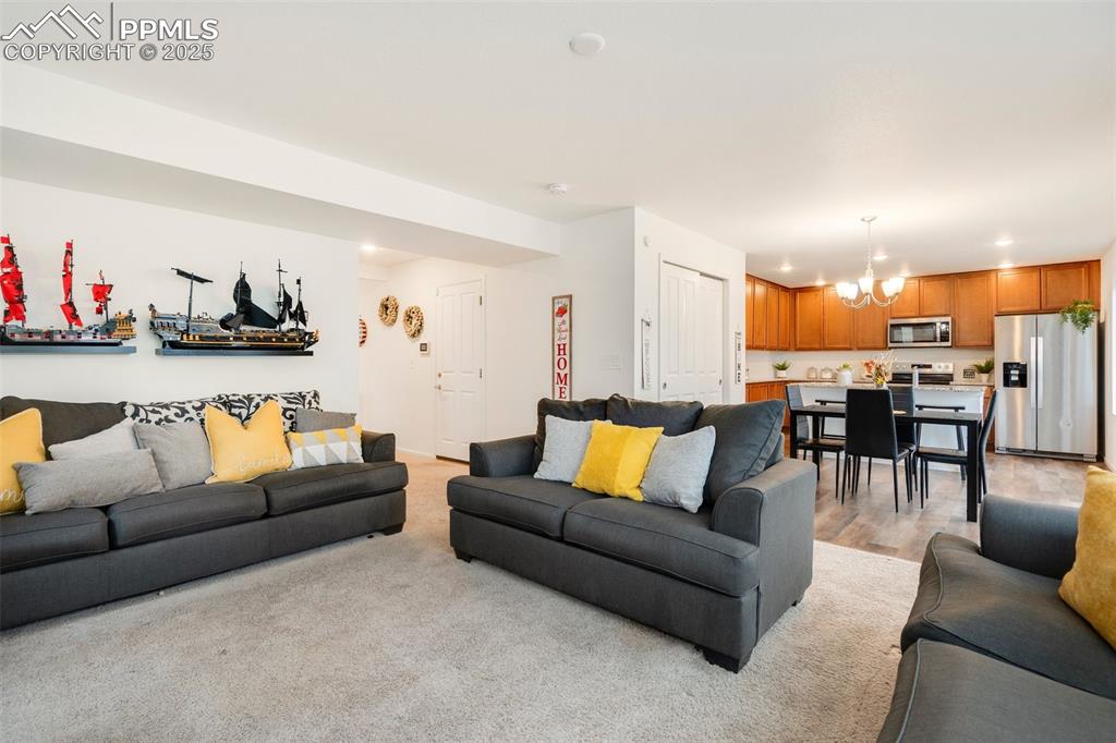 Image 5 of 29: Living room with light wood-style floors and an inviting chandelier