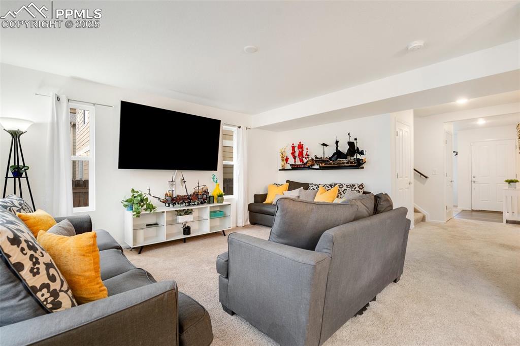 Image 6 of 29: Living room with stairs and light colored carpet