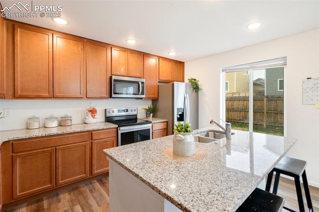 Image 9 of 29: Kitchen featuring light stone counters, wood finished floors, stainless ste