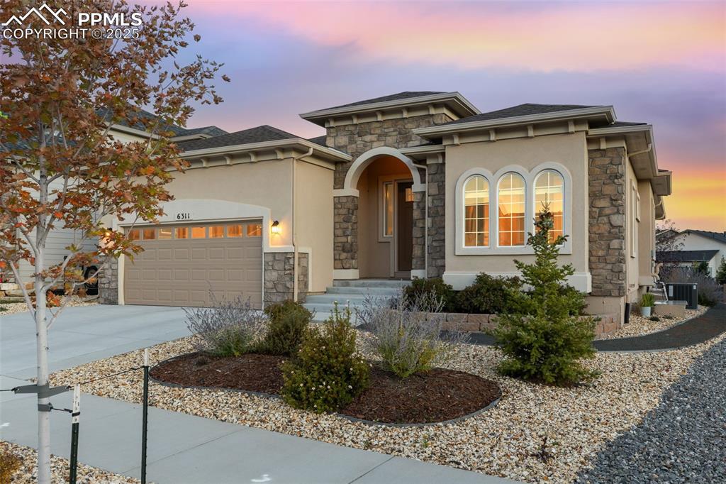 Image 10 of 49: Mediterranean / spanish house with stone siding, concrete driveway, and stu