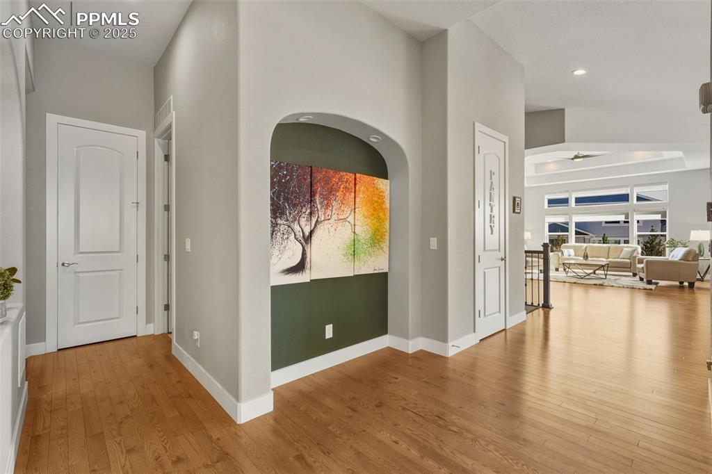 Image 13 of 49: Hallway with light wood-style floors, arched walkways, and recessed lightin