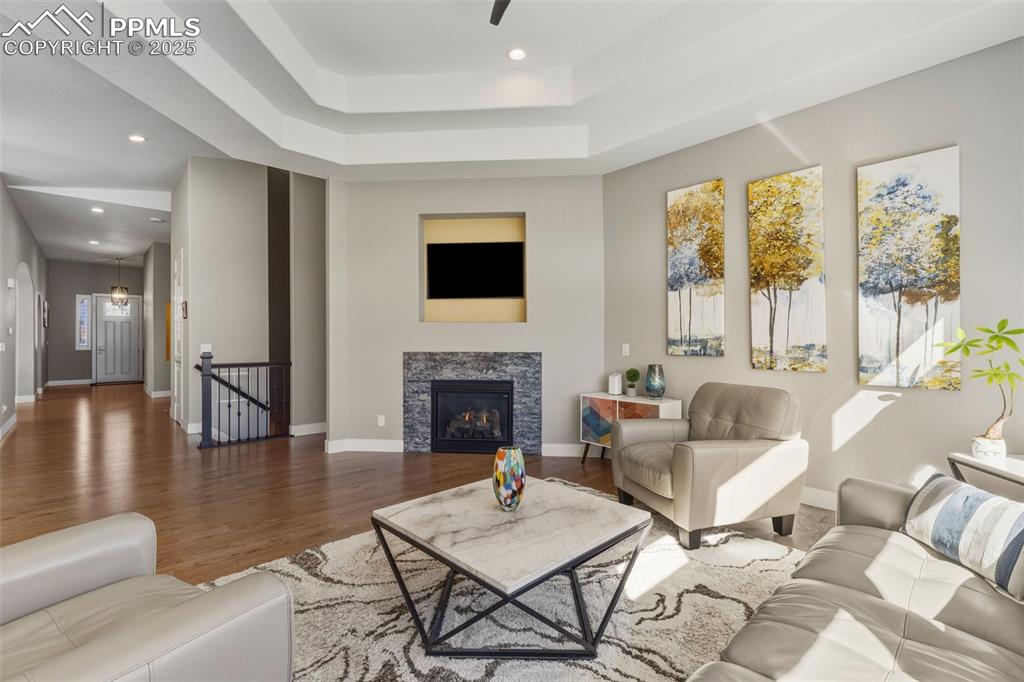 Image 15 of 49: Living room with recessed lighting, wood finished floors, a warm lit firepl