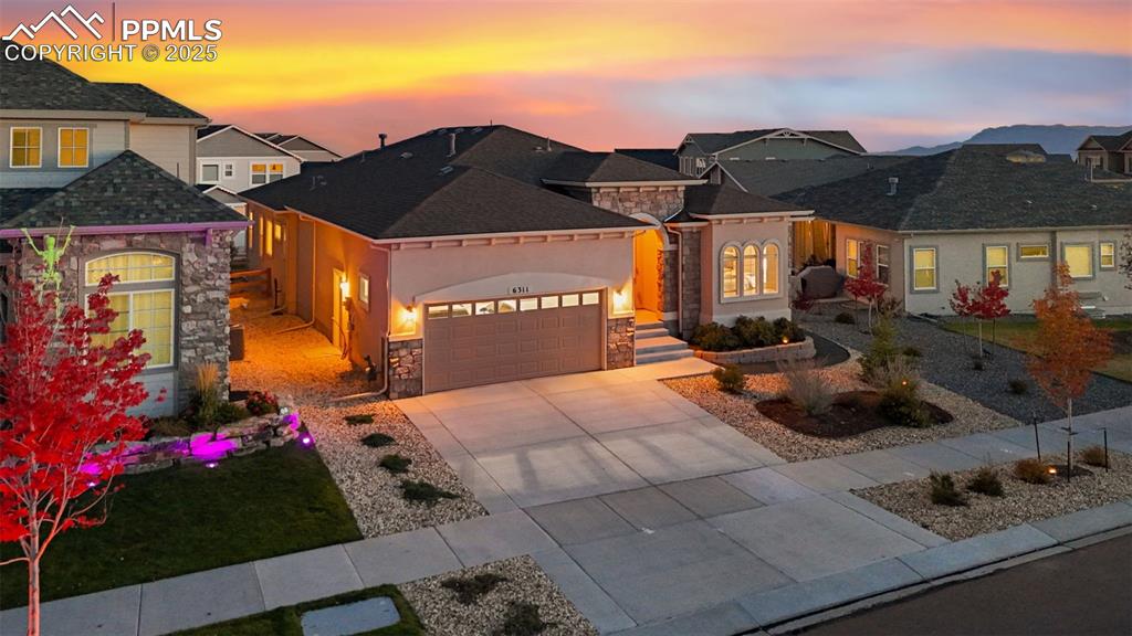 Image 2 of 49: View of front of property with stone siding, a garage, and concrete drivewa