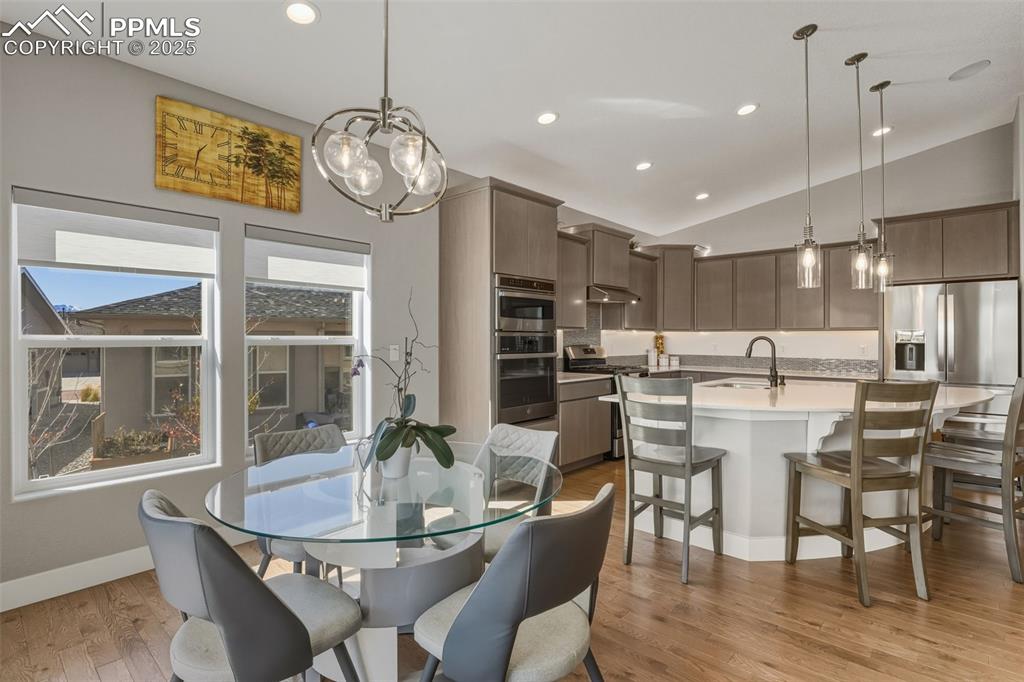 Image 20 of 49: Dining room featuring light wood-style floors, vaulted ceiling, recessed li