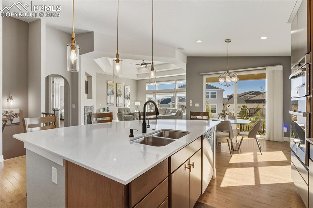 Image 22 of 49: Kitchen featuring a ceiling fan, decorative light fixtures, light wood fini