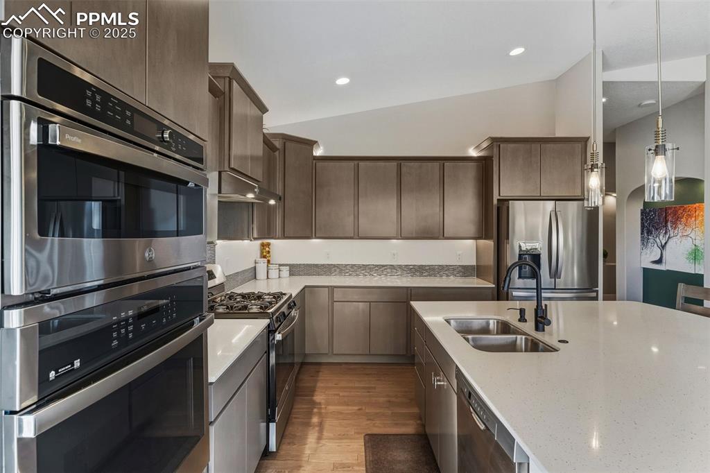 Image 25 of 49: Kitchen with stainless steel appliances, vaulted ceiling, light wood-style 
