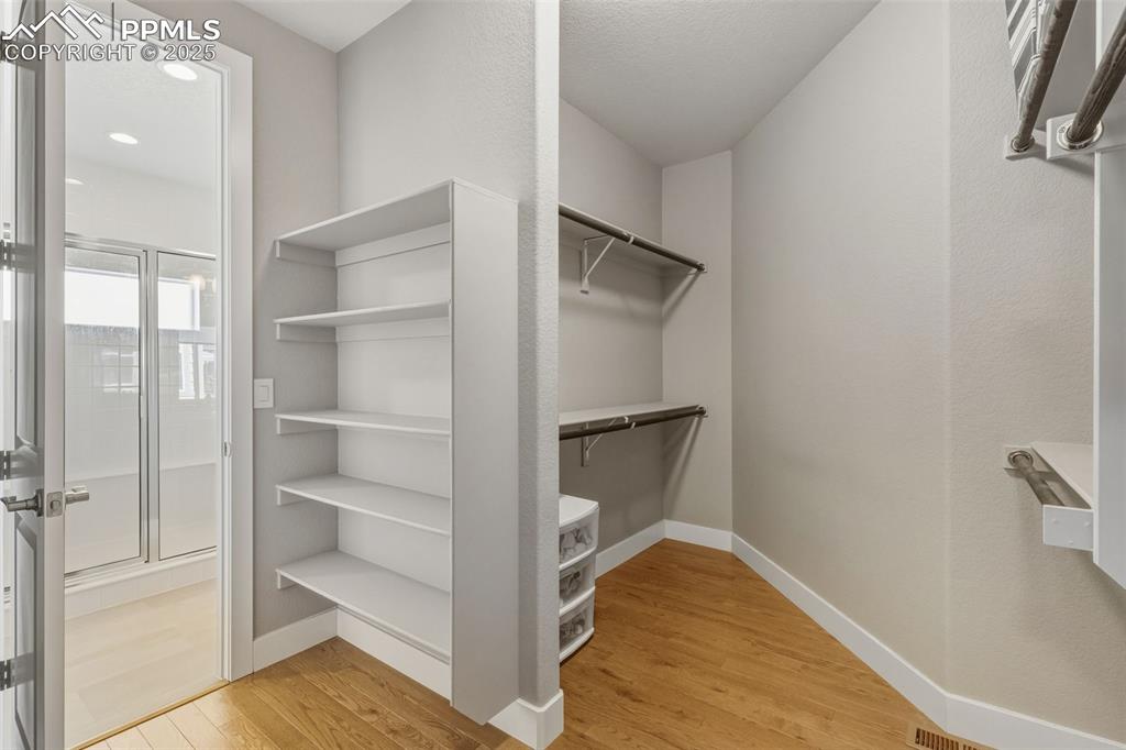 Image 27 of 49: Walk in closet with light wood-style floors