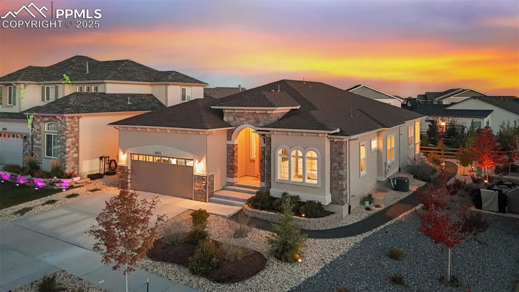 Image 3 of 49: View of front of home featuring stone siding, driveway, a garage, roof with