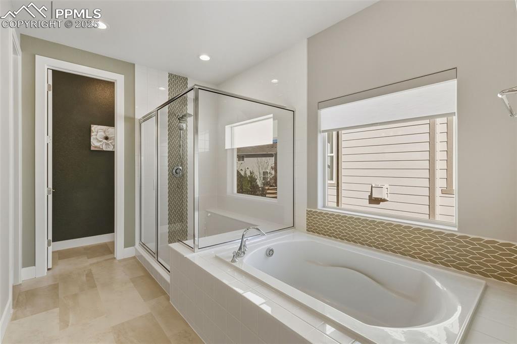 Image 32 of 49: Full bathroom featuring a garden tub, a stall shower, recessed lighting, an