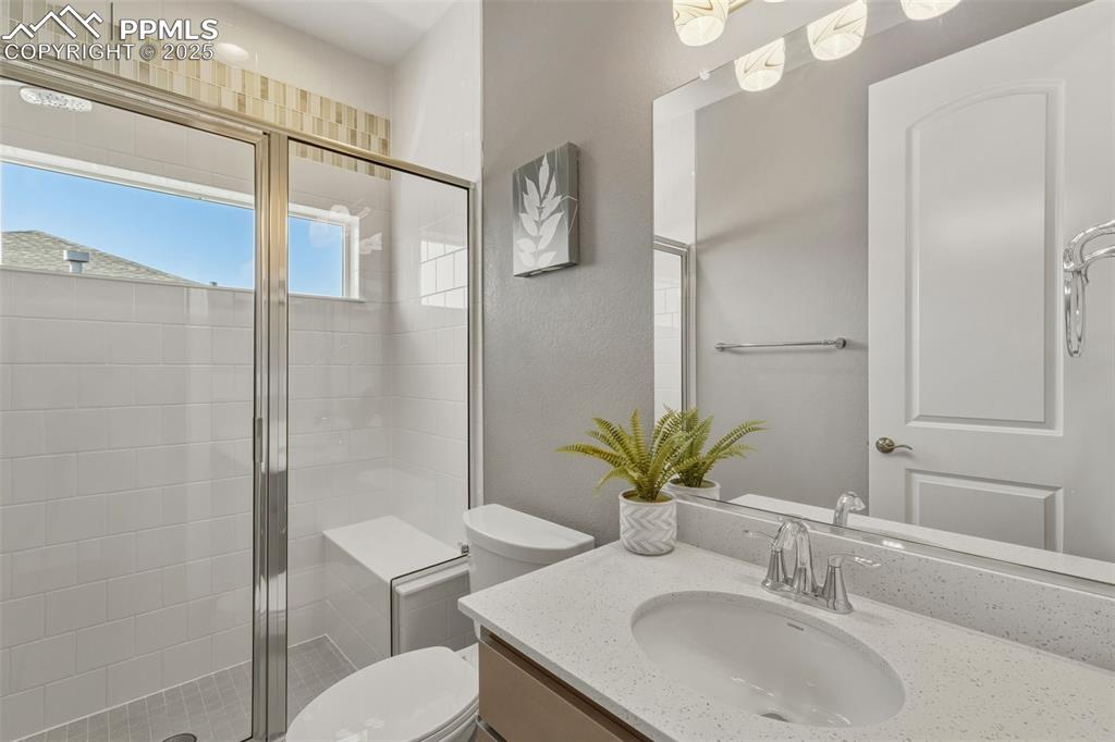Image 36 of 49: Full bath with vanity, a shower stall, and a textured wall