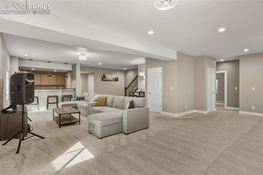 Image 38 of 49: Living area featuring recessed lighting, light colored carpet, and stairs