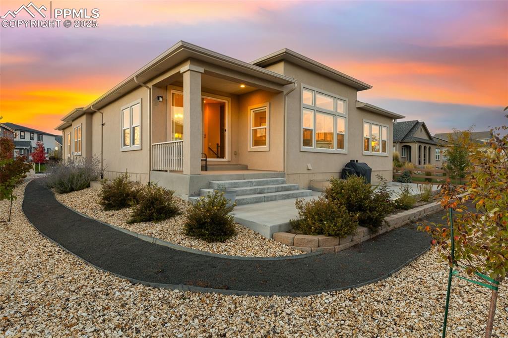 Image 47 of 49: Back of property at dusk featuring stucco siding and a porch