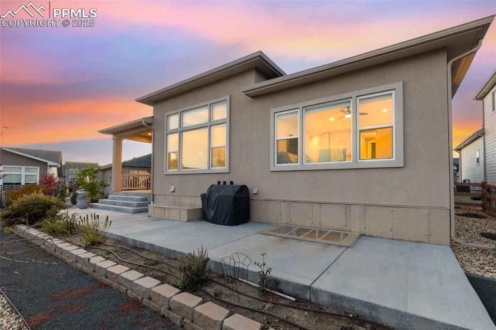 Image 48 of 49: Back of property at dusk with stucco siding and covered porch