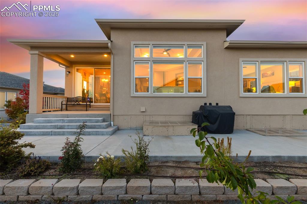 Image 49 of 49: Back of house at dusk with stucco siding and a patio