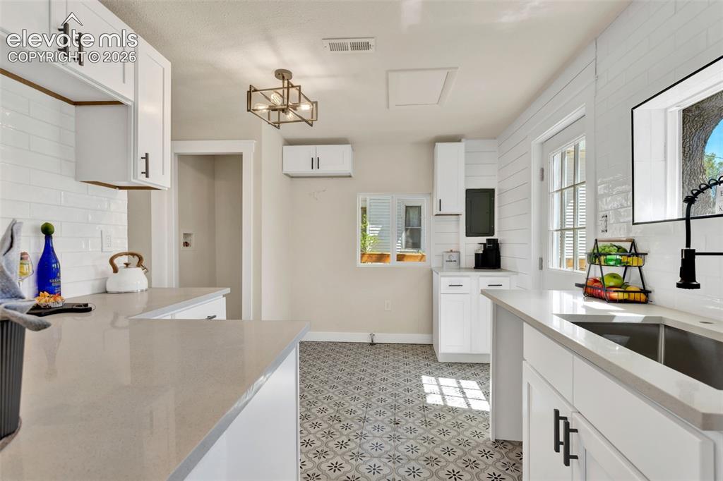 Image 13 of 26: Kitchen featuring white shaker-style cabinetry with matte black hardware, l